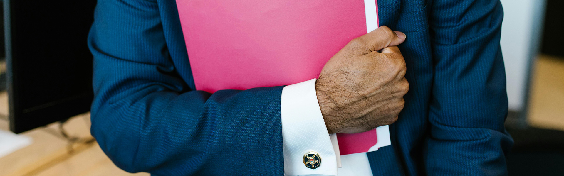 Dokumente die man braucht Ein Mann in einem dunkelblauen Anzug hält einen pinkfarbenen Ordner in der Hand